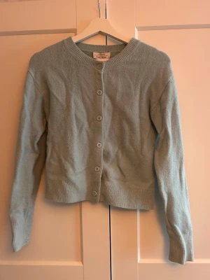 Ljusblå kofta - Söt ljusblå kofta från Gina Tricot med rund halsringning och knappar framtill. Koftan har långa ärmar och ribbade muddar vid ärmslut och nederkant. 