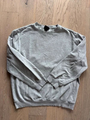 Grå sweatshirt från H&M Relaxed Fit - En enkel och stilren grå sweatshirt från H&M i modellen Relaxed Fit. Tröjan har rund hals, långa ärmar och ribbade muddar vid ärmslut och nederkant. Perfekt för en avslappnad och casual look.