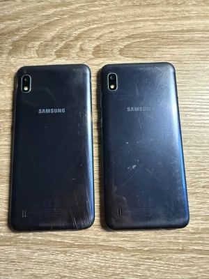 Svarta Samsung Galaxy Androidmobiler - Två svarta Samsung Galaxy Androidtelefoner med enkel bakkamera och LED-blixt. Baksidan är i plast och har Samsung-loggan centrerad. Telefonerna har rundade hörn och en stilren design med stor skärm på framsidan.