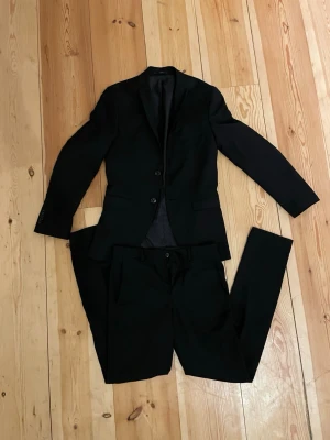 Jack & Jones Kostym 42 - Svart Jack & Jones kostym i storlek 42. Modell Super slim och passar perfekt till festliga tillfällen som skolbalen. Passar dem som är 170-175 skulle jag säga. Plagget är endast använt en gång så väldigt bra skick. Om ni har frågor eller funderingar är det bara att höra av sig. 