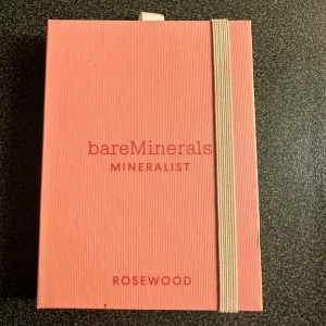 bareMinerals Mineralist Rosewood palett - Säljer en bareMinerals Mineralist ögonskuggspalett i färgen Rosewood. Paletten innehåller sex nyanser: Blossom, Burnt Rose, Marigold, Sepia, Wildflower och Primrose i jordnära och rosa toner. Förpackningen är rosa med elastiskt band och har en stilren design.