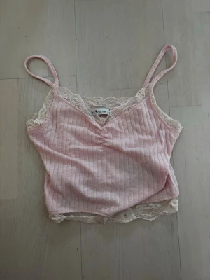 Ljusrosa linne - Söt ljusrosa topp med spetsdetaljer. Ribbat tyg och justerbara axelband. Väldigt fin till både jeans och kjol 🌸Säljer eftersom den tyvärr inte kommer till användning. 
