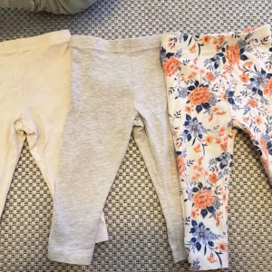 3-pack leggings i neutrala färger & blommigt - Tre par leggings i mjukt material: ett par i beige, ett i ljusgrått och ett par med blommigt mönster i orange och blått på vit botten. Perfekta för en avslappnad och trendig look. Resår i midjan för skön passform.