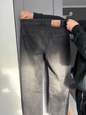 Grå tvättade jeans från Montén - Snygga grå jeans från Montén med tvättad look och raka ben. Jeansen har klassisk femficksmodell, knappgylf och en läderpatch med logga bak i midjan. 