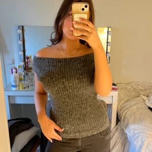 Grå off shoulder stickad topp - Säljer en snygg grå stickad topp med off shoulder-modell. Toppen är ribbstickad och sitter figurnära, perfekt för att skapa en trendig look. Passar till både jeans och kjol för en cool stil. Från zara