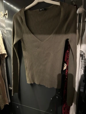 Olivgrön ribbad tröja Gina Tricot - ) Säljer en olivgrön, ribbstickad tröja sop från Gina Tricot. Tröjan har djup v-ring insertning, lå commngärmade ärmar och figurnära passform. Perfekt för dig som gillar stilrena och trendiga plagg. Materialet är mjukt och stretchigt för extra komfort.