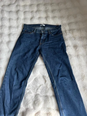 Blå raka jeans från Perfect Jeans - Säljer ett par klassiska blå jeans från bikbok Perfect Jeans i rak modell. Jeansen har fem fickor, normal midja och stängs med knapp och dragkedja. Materialet är slitstarkt denim i 100% bomull. Perfekta till en avslappnad och trendig look.
