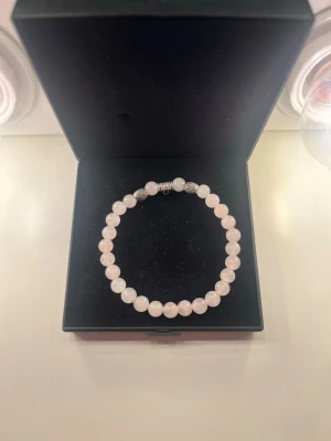 Armband med ljusrosa pärlor - Snyggt armband med runda ljusrosa pärlor, trädda på elastisk tråd. Pärlorna har en mjuk glans och armbandet har ett enkelt metallspänne. Perfekt accessoar för att lyfta din stil.