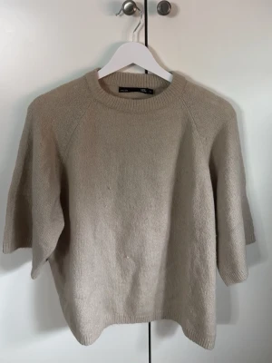 Beige stickad tröja från Lager 157 - Stickad tröja i beige från Lager 157 med rund halsringning och halvlånga ärmar. Tröjan har en avslappnad passform och ribbade detaljer vid hals, ärmslut och nederkant. Perfekt för lager på lager och enkel att matcha med olika stilar. Aldrig använt men är smått nopprig💗