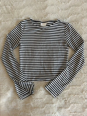 Randig långärmad topp  - Snygg randig topp i svart och vitt. Kortare modell med långa ärmar. Mjuk och skön i material. I fint skick från Ginatricot i storlek 134/140cm.