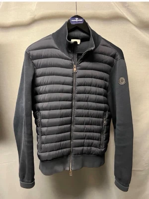 Moncler cardigan M - Säljer denna sjukt feta moncler black label cardigan! Garanterad äkthet. Size M sitter som S. Modellen är 180cm. Skick 8/10 lite slitna muddar annars superfin! Nypris hela 14.000kr! Hör av dig vid minsta fundering 🤩