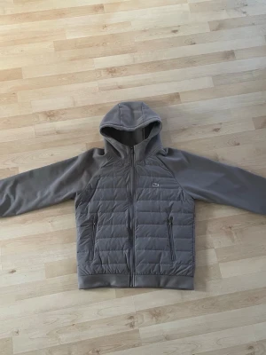Grå Lacoste cardigan  - En riktigt fet cardigan från Lacoste. Använd men ingen syn på användning eller slitage. Skick 9/10🤩🤩 storlek S. Köpt på plick. Pris ej hugget i sten💸💸