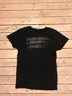 Svart Saint Laurent t-shirt med tryck - Cool svart t-shirt från Saint Laurent med vitt grafiskt tryck på bröstet. Klassisk rund hals och korta ärmar. Perfekt för dig som gillar en edgy och stilren look. Tillverkad i mjuk bomull för skön känsla hela dagen.