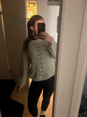 Beige stickad tröja med mönster - Säljer en beige stickad tröja med snyggt hålmönster framtill. Tröjan har rund halsringning, långa ärmar och är lite oversized för en avslappnad look. Perfekt att matcha med jeans eller leggings. Materialet känns mjukt och bekvämt.