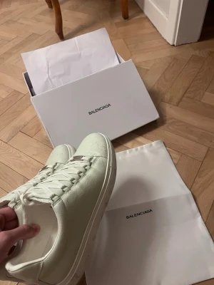 Vita sneakers i läder - Stilrena vita sneakers  i mjukt läder med klassisk låg profil och vita skosnören. logga i guld på insidan. Kommer med originalkartong och dustbag. Perfekta för dig som gillar minimalistisk och lyxig stil.