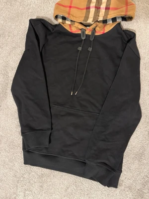 Burberry hoodie  - Svart burberry hoodie med en snygg design på luvan och med en bra passform och bra material. 