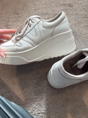 Vita chunky sneakers med platåsula - Säljer ett par vita chunky sneakers med hög platåsula och snörning. Lite slitna så därför att bra pris!!💕💕