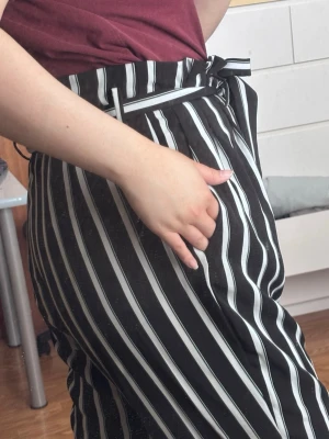 Svartvita randiga kostymbyxor - **** har råkat dra av ordinarie knapp på knäppningen i midjan men finns en extra knapp i byxan. **** super härligt material som inte skrynklar. Paper-bag modell. De är svart,vit och mörkgröna ränder.