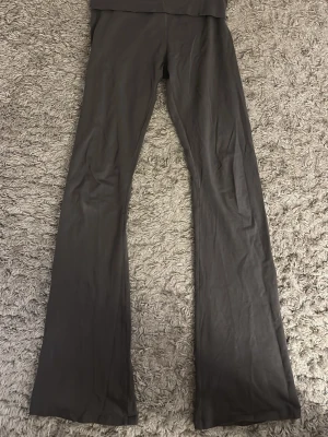 Grå bootcut leggings - Säljer ett par grå leggings med bootcut-ben. De har hög midja och är gjorda i ett stretchigt material som sitter bekvämt. Perfekta för dig som vill ha en enkel och stilren look med lite extra flair i benen.