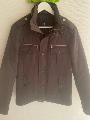 Brun fodrad Riley field jacket - Otroligt snygg brun fodrad Riley field jacka/field jacket. Passar perfekt nu till slutet av vintern och våren.  Defekt: saknar knapp, se näst sista bilden. Men ersättningsknappar medföljer så det går att laga.  Storlek 46 vilket motsvarar storlek S. Priset kan såklart diskuteras!