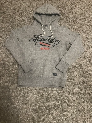 Grå hoodie från Superdry Jeans - Säljer en riktig stilren och fet superdry hoodie i gott skick. Den passar som bäst om man ligger runt 165cm. Ligger ute mest som intressekoll men bra bud kan leda till en snabbaffär! 🙌 Endast seriösa köpare! ☺️