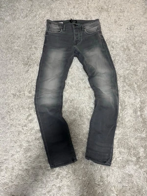 Grå vintage jeans från jack and jones - Säljer ett par snygga gråa jack and jones jeans. Storlek 28/32. Har skön tvätt både framtill och baktill. Fraktar dagligen.