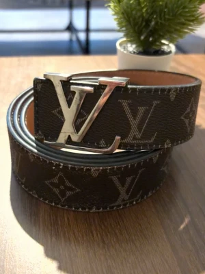 Bälte  - Snyggt brunt skärp med klassiskt -monogram och stor silvrig -spänne. Skärpet har en exklusiv känsla och är gjort i skinn med beige insida. Perfekt accessoar för att lyfta din outfit.