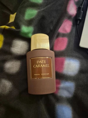 Date Caramel parfym - Date Caramel Eau de Parfum 100 ml från Paris Corner.                                                                                      DOFTNOTER: Toppnoter: Dadlar, Kaffe, Apelsin Hjärtnoter: Kola, Socker, Bensoin Basnoter: Vanilj, Amber, Sandelträ