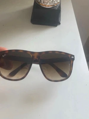 Ray ban boyfriends  - Snygga solglasögon från Ray-Ban med fyrkantig form och brunmelerad båge. Glasen är tonade i brunt och bågarna har en klassisk design som passar till många stilar. Perfekta för soliga dagar och ger en cool vibe.