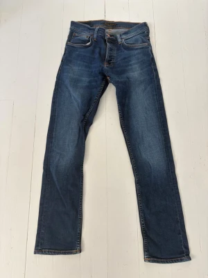 Blå jeans från Nudie Jeans Co - Säljer ett par klassiska blå jeans från Nudie Jeans Co i storlek 30/30. Jeansen är i mycket bra skick. Nypris:1600kr. Mitt pris ä: 599kr
