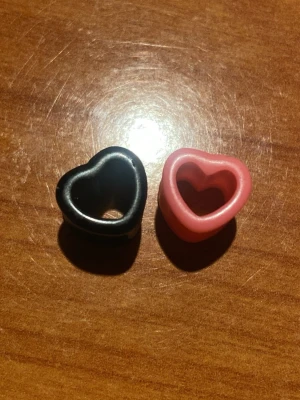 Hjärtplugg örhängen svart & rosa - Två hjärtformade pluggar till öronen i svart och rosa. Diameter är 9 mm. Säljes för 40kr