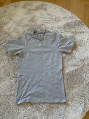 YoungLA compression - Säljer en stilren ljusgrå t-shirt från YoungLA med diskret logga på bröstet. T-shirten har rund halsringning och korta ärmar. Perfekt för dig som gillar enkel och clean stil.