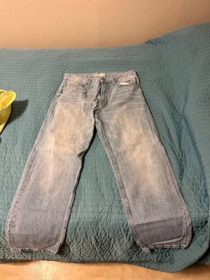 Ljusblå raka jeans med slitningar - Säljer ett par ljusblå jeans med raka ben och tydliga slitningar framtill. Jeansen har klassisk femficksmodell och normal midja. Perfekta för en avslappnad och trendig look.