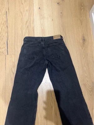 Svarta/mörkgråa  jeans från NA-KD - Säljer ett par svarta/mörkgråa raka jeans från NA-KD med klassisk femficksmodell och bälteshällor. Jeansen har en snygg tvättad finish och är tillverkade i ett mjukt denimtyg som ger en avslappnad look. Perfekta till alla typer av outfits!