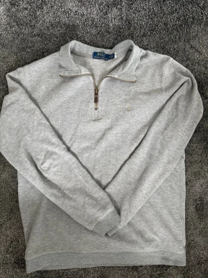 Ralph Lauren Quarter Zip - Grå Ralph Lauren Quarter Zip i storlek M. Bra skick förutom ett liten rivmärke (bild 4/4) som endast är ytligt.