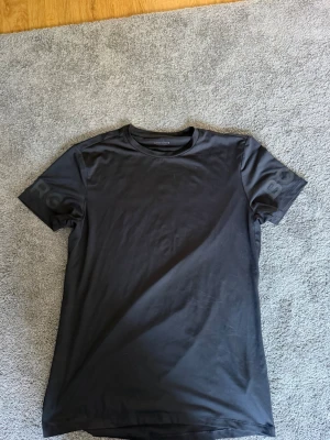 Svart Björn Borg t-shirt - Snygg svart t-shirt från Björn Borg med diskret logga på ärmen. Klassisk rund halsringning och korta ärmar. Tillverkad i mjuk bomull som känns skön mot huden. Perfekt till jeans eller shorts för en clean look.