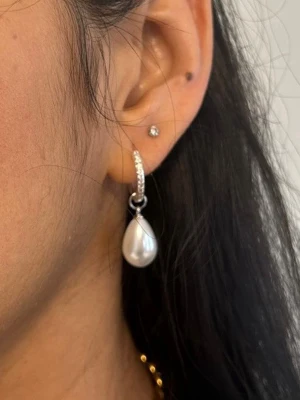 Silvriga S925 örhängen med droppformade pärlor - Priset avser ett par örhängen och det finns även i guldpläterad variant  Material: Sterling silver med zirkoniakristaler och ABS på pärlimitationen  Längd: ca 30 mm Nickelfria och handgjorda.  