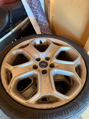 Ford fälg med Continental däck - Säljer en silverfärgad Ford aluminiumfälg med Continental däck. Fälgen har fem ekrar och en sportig design, passar till Ford-bilar. Däcket är märkt Continental och har tydligt mönster. Perfekt för dig som vill byta ut eller uppgradera dina hjul.