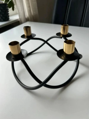 Svart ljusstake i metall från Dorre - Snygg och stilren ljusstake i svart metall med fyra hållare i mässingsfärg.