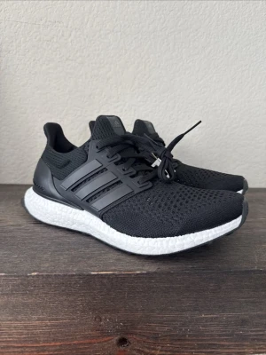 Adidas Ultraboost svarta sneakers - Svarta Adidas Ultraboost sneakers med stickad ovandel och klassiska tre ränder i plast på sidorna. Skorna har en vit, responsiv Boost-sula och svart hälkappa. Bäst på marknaden!