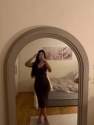 Brun klänning från Gina Tricot XS - Säljer en snygg brun tight klänning med v-ringning och ärmlös design. Klänningen är midilång och har en figurnära passform som framhäver siluetten. Perfekt för dig som gillar stilrena och enkla plagg med en modern touch.