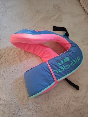 Blå och rosa simväst från Nabaiji - För barn som väger runt 25-35kg. Säljer en snygg simväst från Nabaiji i blått och rosa med mintgröna detaljer. Perfekt för strandhäng och bad, västen har justerbara remmar och är lätt att ta på. Materialet är mjukt och bekvämt mot huden. Passar för simträning och vattenlek.