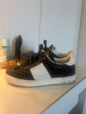 Valentino flycrew glitter  - Snygga sneakers från Valentino i svart och vitt med glittriga detaljer. Skorna har klassisk snörning och en chunky vit sula med nitar på sidan. Perfekta för dig som vill sticka ut med en exklusiv touch och cool design. Skorna saknar även tre nitar men inget man tänker på överlag.box,snören,nitar osv kommer inte med utan bara skorna💕