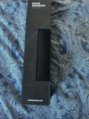 Sharkgaming musmatta  900x400mm (ny) - Stor svart musmatta från Sharkgaming, perfekt för gaming eller kontor. Mått 900x400mm ger gott om plats för både mus och tangentbord. Tillverkad i mjukt material för smidig rörelse och bra precision.