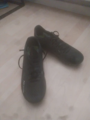 Svarta fotbollsskor från nike  - Säljer ett par svarta fotbollsskor från NEXEN med snörning och låg profil. Skorna har en stilren design med diskreta detaljer och grön insida. Perfekta för dig som vill ha bra grepp och kontroll på planen.