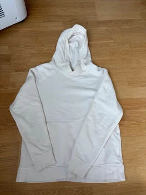Vit hoodie med huva och ficka - En stilren vit hoodie med huva och magficka framtill. är från H&M och i storlek 158/164.