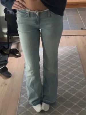 Nelly jeans  - Säljer ett par ljusblå bootcut jeans med låg midja och klassiska fem fickor. Jeansen har en avslappnad passform och är perfekta för en trendig vardagslook. Materialet är denim och färgen är riktigt fräsch ljusblå.