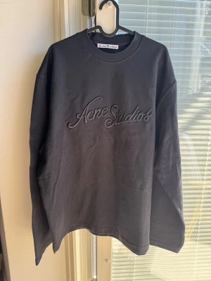 Svart sweatshirt från Acne Studios - Svart oversized sweatshirt från Acne Studios med broderad logga framtill. Tröjan har rund halsringning och långa ärmar. Perfekt för en chill och stilren look.