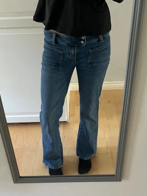 Lågmidjade jeans  - Säljer ett par blå jeans från Lager 157 med raka ben och dubbla knappar i midjan. I fint skick. 