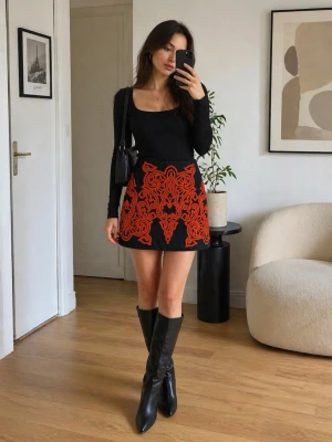 Svart minikjol med rött mönster Guess - Snygg svart minikjol från Guess med iögonfallande rött broderat mönster framtill. Kjolen har en figurnära passform och dragkedja i sidan. Perfekt för dig som vill sticka ut med en unik och trendig look.